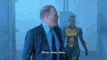 a man in a suit says whoa whoa whoa in front of a superhero