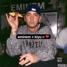 eminem is wearing a blue hat and holding a piece of food in his hand .