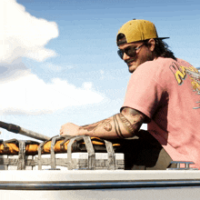 a man wearing a pink shirt that says ' nz ' on the back sits on a boat