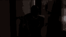 a man in a suit and tie is opening a door in a dark room .