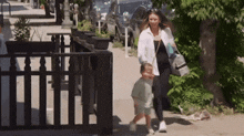 a woman and a child are walking down a sidewalk .