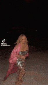 a woman in a polka dot dress is standing in front of a fireworks display with tiktok written on the bottom