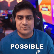 a man wearing headphones and a blue shirt with the word possible written on it