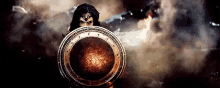 wonder woman is holding a shield in front of a smoke filled room .