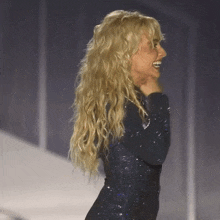 a woman with blonde curly hair wearing a blue sequined dress