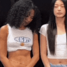 two women are standing next to each other and one of them is wearing a crop top with the word light on it