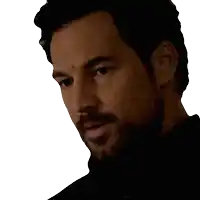a man with a beard wearing a black shirt looks down