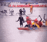 a group of people are rowing boats in the water and one of them is wearing a shirt that says ' red bull ' on it
