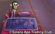 a man in a suit and tie is driving a red car with a monkey mask on his face