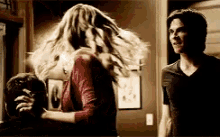 a man and a woman are standing next to each other in a room . the woman is holding the man 's arm .