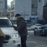 a man standing next to a white bmw with a license plate that says 87