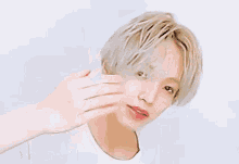 a young man with blonde hair and red lips is giving a thumbs up sign .