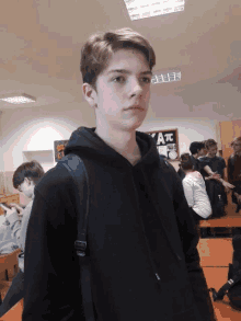 a boy in a black hoodie stands in front of a sign that says ' a '