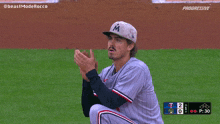 a baseball player wearing a hat with the letter m on it is clapping