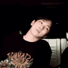 a man wearing a black t-shirt with a flower on it is sitting in a car .