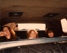 a man smoking a cigarette and two women sitting in the back of a car