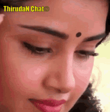 a close up of a woman 's face with a bindi on her forehead and pink lips .