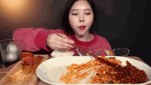a woman is eating a plate of food with chopsticks and a spoon
