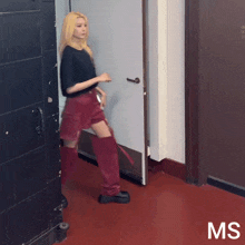 a woman in a black shirt and red shorts is standing in a hallway with the letters ms on the bottom