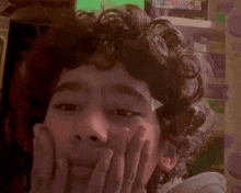 a young boy with curly hair is making a funny face in front of a shelf with a board game called jenga on it