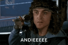 a man with long hair is talking on a cell phone while wearing a headband and a bandana .