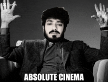 a man with a beard is sitting in a chair with his arms outstretched and the caption absolute cinema