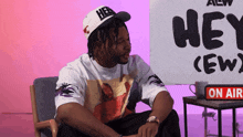 a man sitting in front of a sign that says hey
