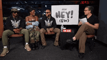 a group of people sitting in front of a sign that says hey ( ew )