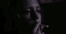 a close up of a woman smoking a cigarette in a dark room