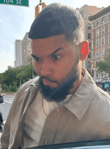 a man with a beard is standing in front of a green sign that says 104 st