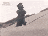a black and white photo of a monster standing on top of a snow covered hill .