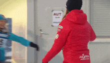 a woman wearing a red jacket with austria power team on the back