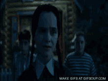 a woman with pigtails is standing in a dark room with a man in a striped shirt .