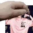 a hand is covering a man 's face in a pink t-shirt .