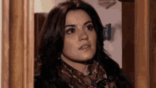 a woman wearing a scarf and earrings looks out of a doorway