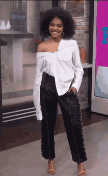 a woman in a white off the shoulder shirt and black pants