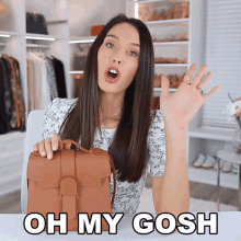 a woman is holding a brown purse with the words oh my gosh above her