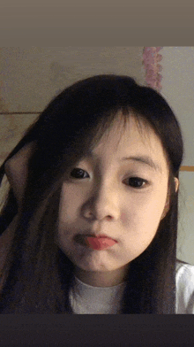 a girl with long black hair is making a face