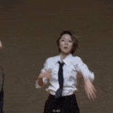 a woman wearing glasses and a white shirt and tie is dancing on a stage .
