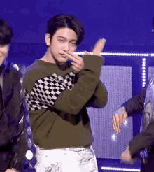 a man in a green and black checkered sweater is dancing on stage .