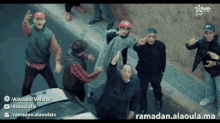 a group of men are dancing in front of a car with ramadan.alaoula.ma on the bottom right