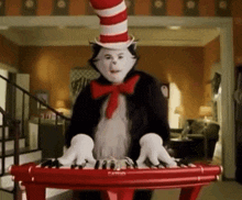 cat in the hat is playing a red piano