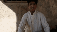 a man in a white shirt sits in front of a wall