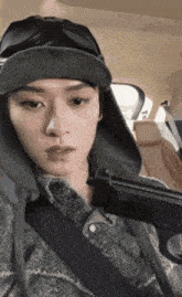 a man wearing a hat and goggles is holding a gun in his hand
