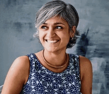 a woman with gray hair is smiling and wearing a blue tank top