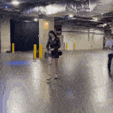 a woman in a black leather dress is walking in a parking garage