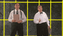 a man and a woman are standing next to each other in front of a yellow grid