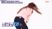 a woman in a pink jacket is dancing in front of a screen that says league