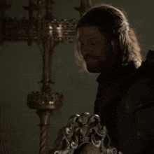 a man with long hair and a beard is smiling and holding a sword