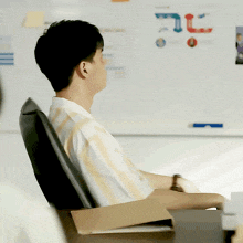 a man sits at a desk with his eyes closed in front of a white board that says fc